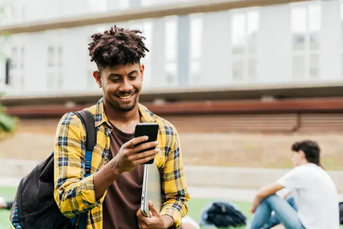 Student smiles down at phones while walking through school campus