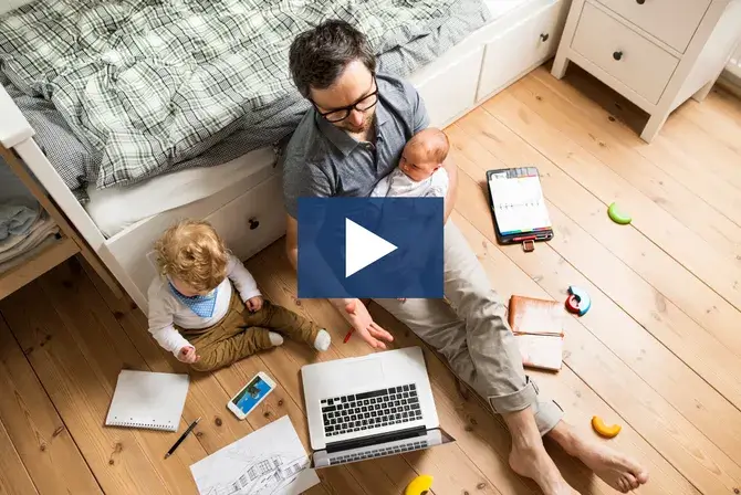 A father holding his baby while doing work
