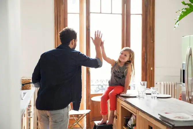 Parent giving young child a high-five
