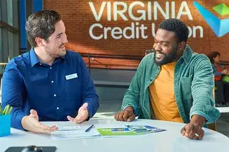 Two individuals having a conversation at a table in a Virginia Credit Union office.