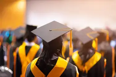 Multiple graduates wearing black and yellow gaps and gowns