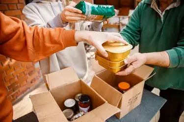 Group of people packing canned goods into card board boxes